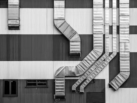 მთავარი Monochrome image showcasing industrial ductwork and vents on a striped building exterior.